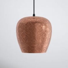 a copper colored pendant light hanging from a black cord on a white wall with an abstract design