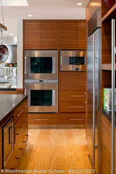 a modern kitchen with stainless steel appliances and wood cabinetry, along with hardwood flooring