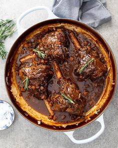 a pot filled with meat and vegetables on top of a table next to a spoon