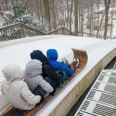 three children are sitting on a sled in the snow