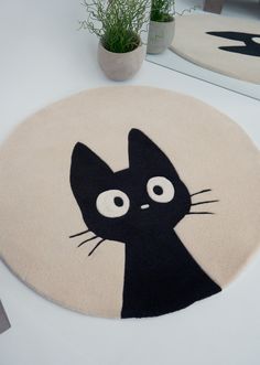 a black cat rug sitting on top of a table next to a potted plant