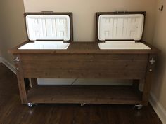 two coolers sitting on top of a wooden table in a room with hard wood floors