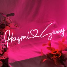 a pink neon sign that says hyanni & sunny on it next to some flowers