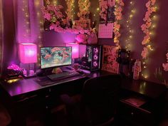 a computer desk topped with a desktop computer next to a purple wall covered in lights