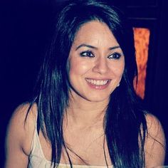 a woman with long dark hair smiling and holding a plate of food in front of her