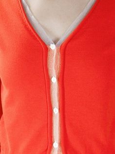 a woman wearing an orange cardigan with white buttons