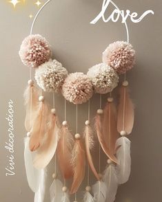 a pink and white dream catcher with pom - poms hanging from it's side