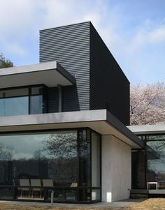 a modern house with large glass windows in the front and side walls that are black and white