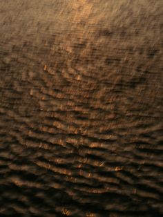 the sun is setting over water with ripples in it