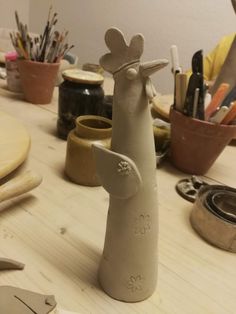 a clay sculpture of a bird on a table with scissors and other crafting supplies