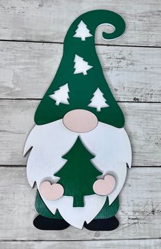 a green and white gnome with a tree on it's head is standing in front of a wood plank wall