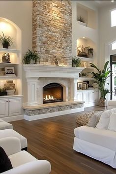 a living room with two white couches and a fireplace in the middle of it