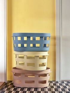 three baskets stacked on top of each other in front of a yellow wall and black and white checkered floor