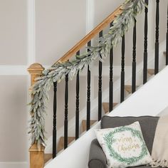 the stairs are decorated with greenery and garlands for holiday decor, along with decorative throw pillows