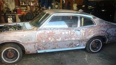 an old car with rust on it in a garage