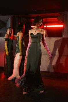 two women in evening gowns standing next to each other with fur on their tails