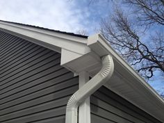 the corner of a house with a gutter hose attached to it