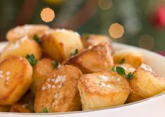 a white bowl filled with fried potatoes covered in powdered sugar and garnished with parsley