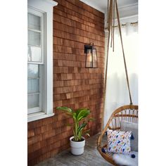 a wooden porch with a hanging chair and potted plant