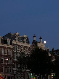 a full moon is seen above some buildings