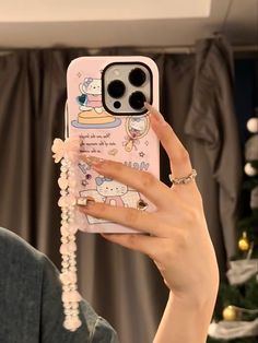 a woman holding up her phone case to take a selfie with hello kitty on it