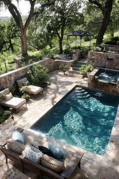 an outdoor swimming pool with lounge chairs and umbrellas next to it, surrounded by trees