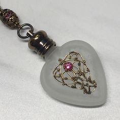 This vintage inspired necklace is made with a small frosted heart crystal perfume bottle. The glass bottle is 40mm across. The neck and gold cap is 10.5 so the overall length is 50.5mm. It can hold 4ml of your favorite perfume. The small cap screws off and it comes with antiqued brass chain that you pick the length! This has a large opening and can put ashes or oils in very Easy. This necklace is very pretty would make a great gift! Ships for free within the US. Heart Perfume Bottle, Heart Perfume, Push Gifts, Gold Cap, Crystal Perfume Bottles, Bottle Jewelry, Gold Caps, Inspired Necklace, Heart Crystal