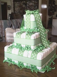 a three tiered green and white cake with polka dots on the top, sitting on a wooden table