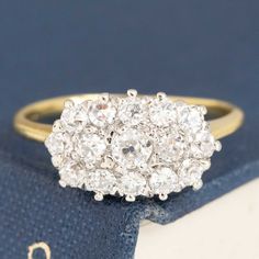 an antique diamond cluster ring on top of a book