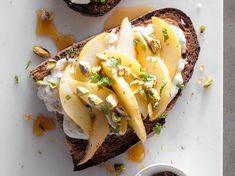 two pieces of bread with apples and whipped cream on them next to a small bowl of pistachio nuts