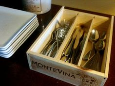 a wooden box filled with silverware on top of a table