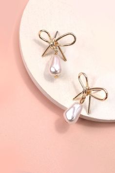 Pearl Dangle Gold Bow Drop Earrings, an exquisite blend of sophistication and charm. These earrings showcase a delicate gold bow design adorned with lustrous pearls, creating a timeless and elegant accessory. The pearl dangles add a touch of refinement and movement, making these earrings perfect for both formal events and everyday wear. Product Details:Width: 1" Length: 1.25"Earring back: PostMetal finish: gold PlatedProduct: Lead & Nickel CompliantAnti-tarnish: Double E-coating Wedding Pearl Drop Earrings With Bow, Gold Feminine Pearl Earrings For Party, Feminine Gold Pearl Earrings For Party, Formal Pearl Drop Earrings With Bow, Formal Pearl Earrings With Bow Detail, Formal Pearl Earrings With Bow, Formal Bow Drop Pearl Earrings, Elegant Rose Gold Earrings With Bow, Elegant Rose Gold Bow Earrings