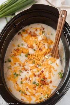 a crock pot filled with cheese and green onions