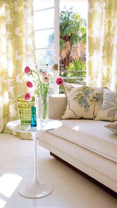 a living room filled with furniture and flowers in vases next to a window sill