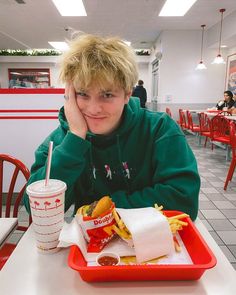 a young man sitting at a table with a tray of food