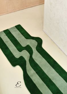 a green and white rug on the floor in a bathroom