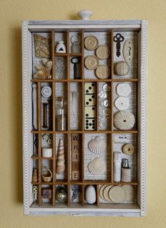 a wooden box filled with lots of different types of buttons and sewing supplies on top of a wall