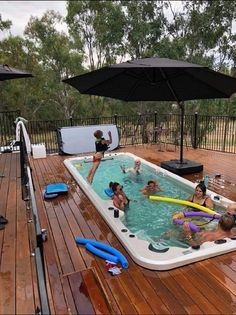 several people are in an outdoor hot tub on a wooden deck with black umbrellas