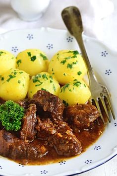 a white plate topped with meat and potatoes