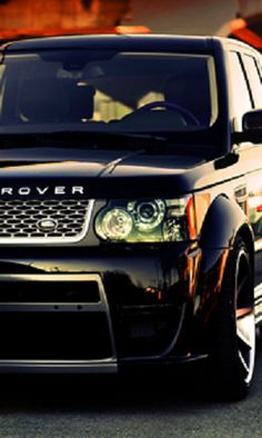 a black range rover is driving down the road