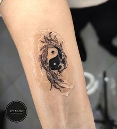 a woman's leg with a tattoo on it that has a black and white yin yang