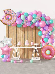 a balloon arch with donuts, balloons and stars on the floor next to it