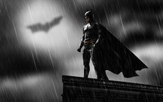 the dark knight standing on top of a building in the rain