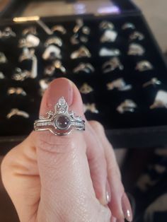 a woman's hand holding an engagement ring in front of a box of rings