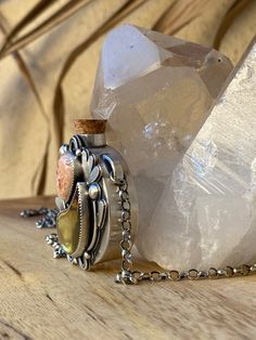 a bottle with a chain around it sitting on a table next to some rocks and crystals