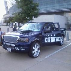 two people standing next to a truck with the word cowboy written on it in white lettering