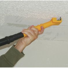 a person is holding a yellow blow dryer in their hand and spraying foam off the ceiling