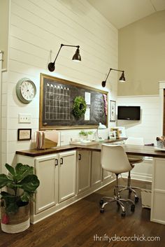 a home office with white cabinets and wooden flooring, along with a chalkboard on the wall