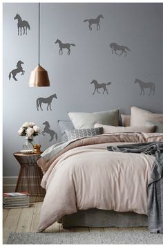 a bedroom with grey walls and horses on the wall