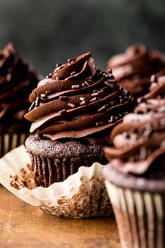 chocolate cupcakes with chocolate frosting and sprinkles are on top of each other